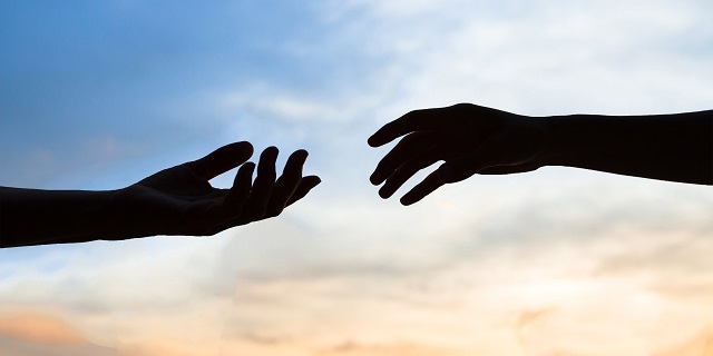 Two hands reaching toward each other symbolising support and understanding